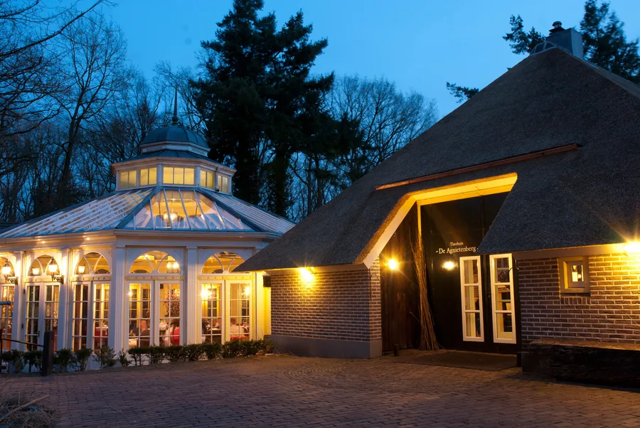 De verlichte Wintertuin en de rieten kap van de entree in het blauwe uur