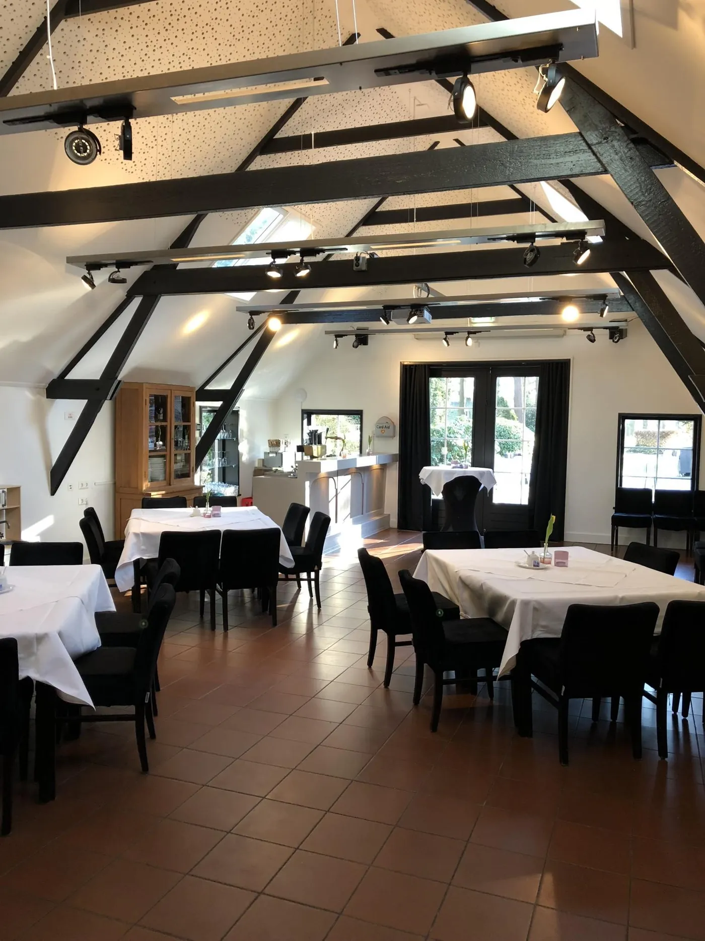 De vernieuwde Hoeve met witte muren, zwarte spanten en gedekte tafels