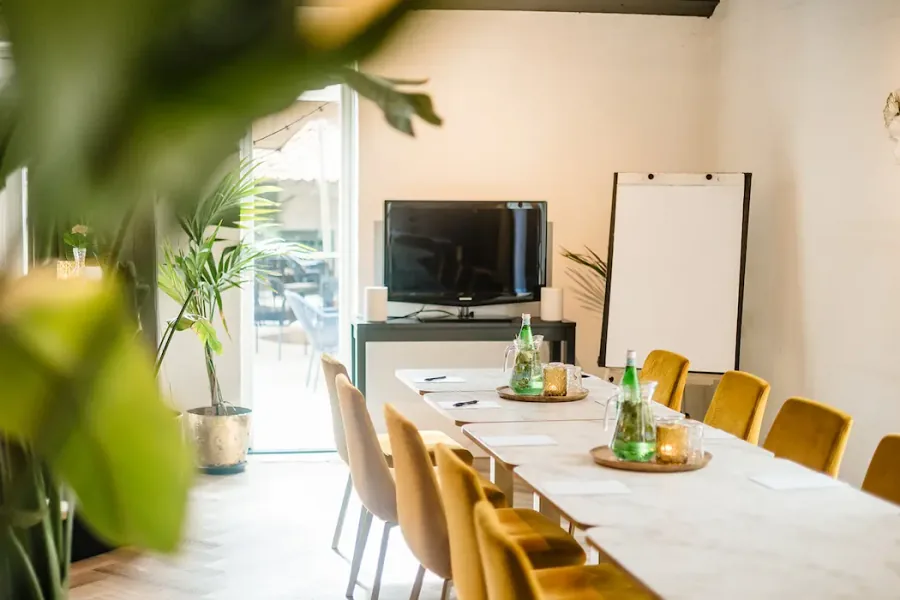 Een vergaderruimte met gele fluwelen stoelen rond een lichte tafel