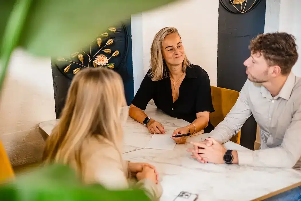 Drie mensen zitten aan een tafel te overleggen in een van de vergaderruimtes