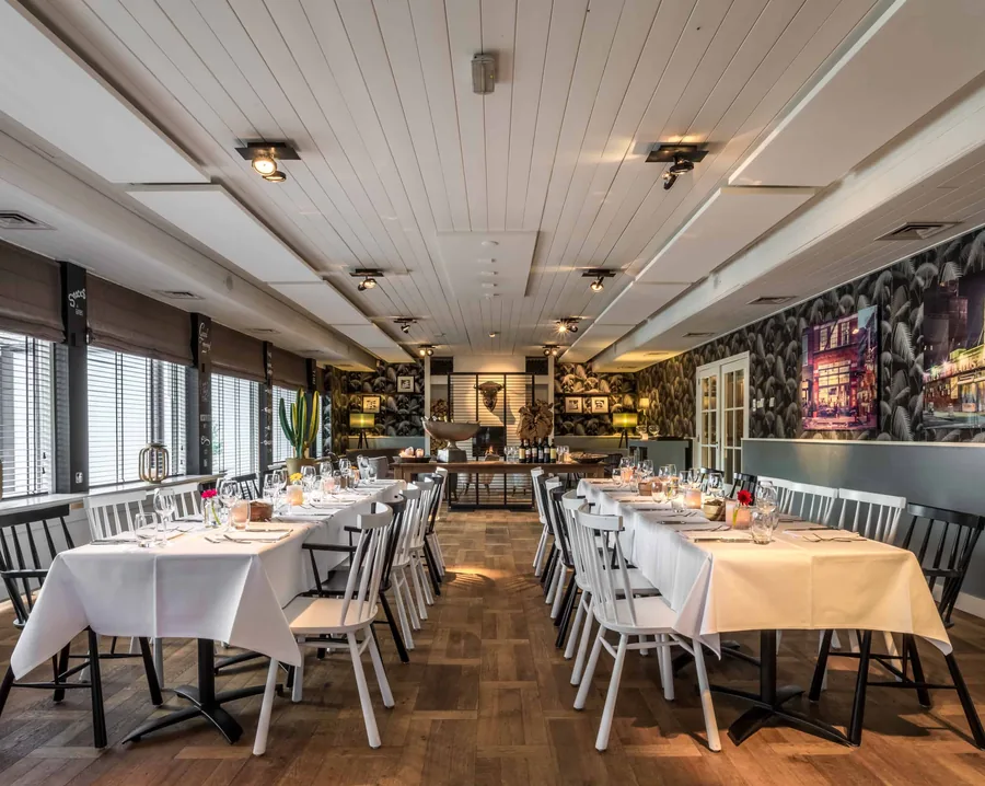 De brasserie met witte tafelkleden, houten stoelen en botanisch behang