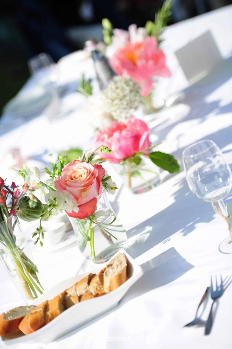 Een roze bruidstaart in etages op een gedekte tafel
