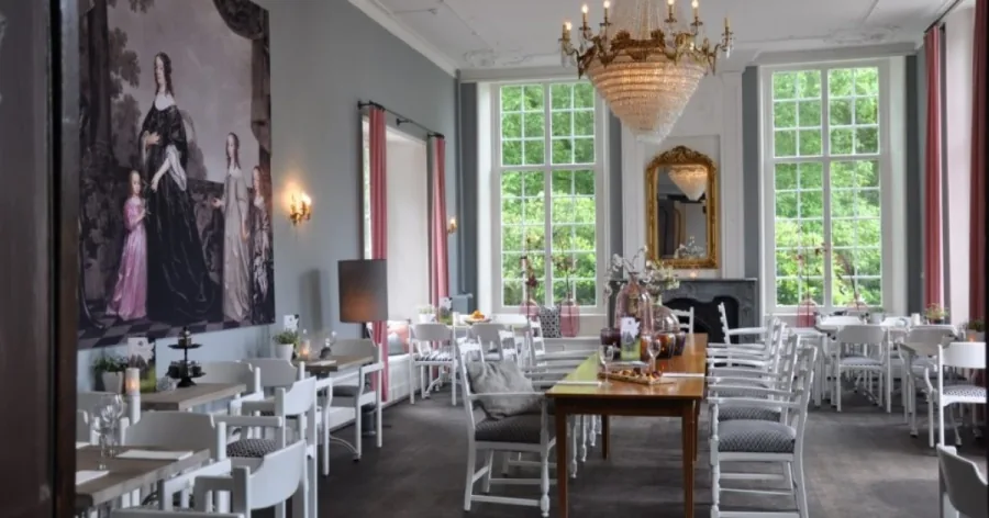 Een lichte zaal in Kasteel Maurick met kroonluchter, schouw en portretten aan de wand