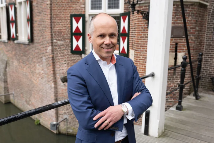 Klaas van Leengoed voor de muur van Kasteel Maurick met het rood-witte wapenschild