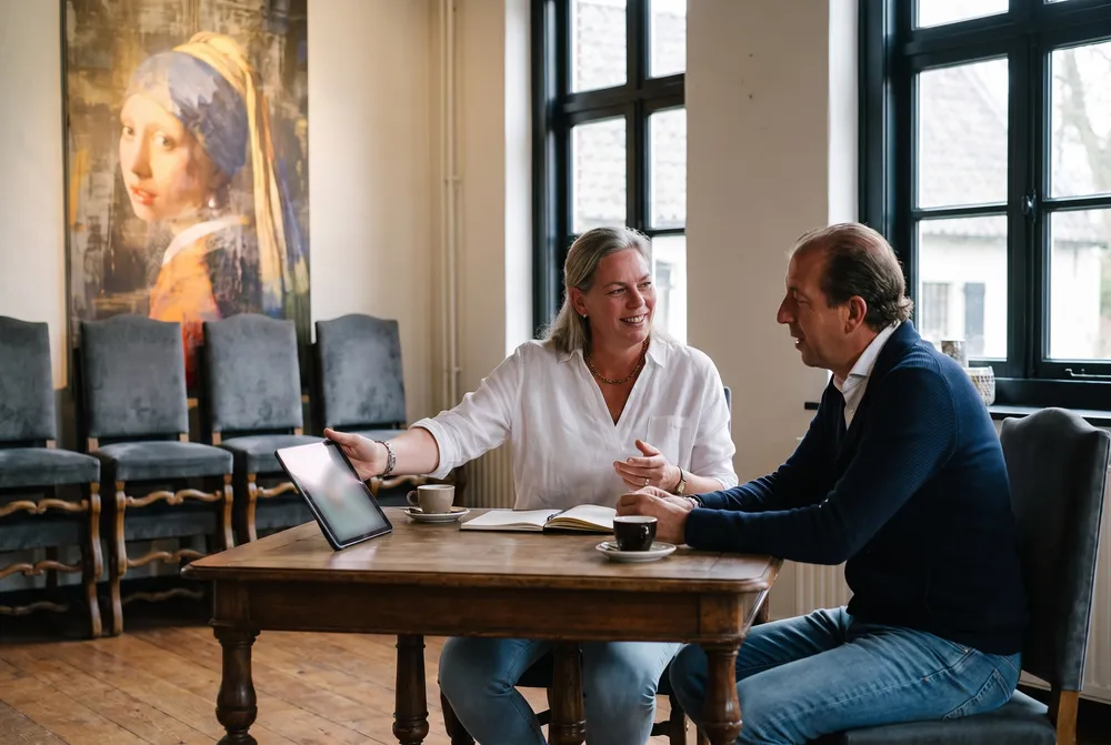Een eventmanager laat aan tafel het scherm zien aan haar gast